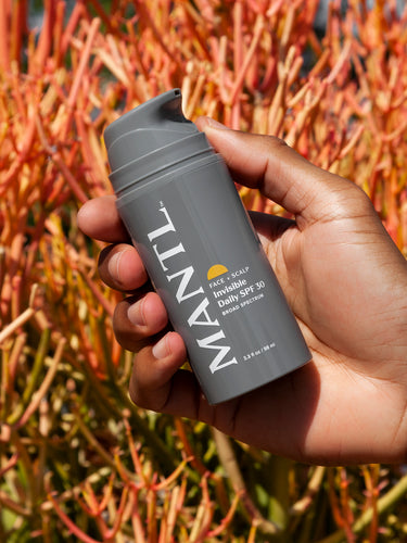 MANTL Invisible Daily SPF 30 in hand in front of a bush